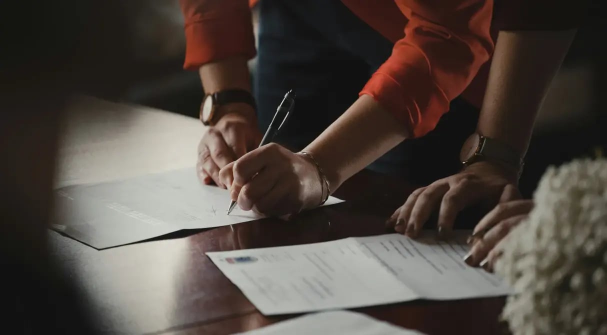 Business professionals reviewing and signing fund service documents at meeting table