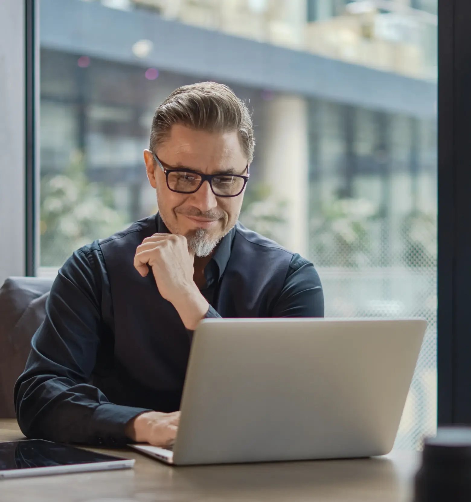Professional businessman in glasses reviewing trademark registration documents on laptop in modern office