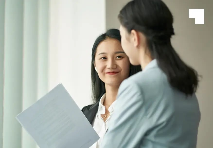 Two professional businesswomen reviewing investment documents during overseas business consultation meeting