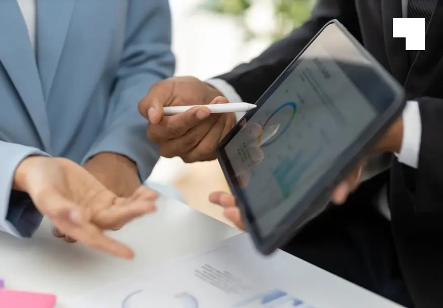 Business professionals reviewing analytics dashboard on tablet during compliance consultation meeting