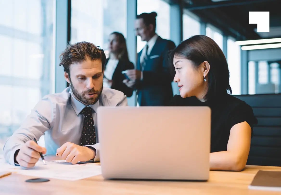 Business professionals reviewing immigration documents on laptop in modern office