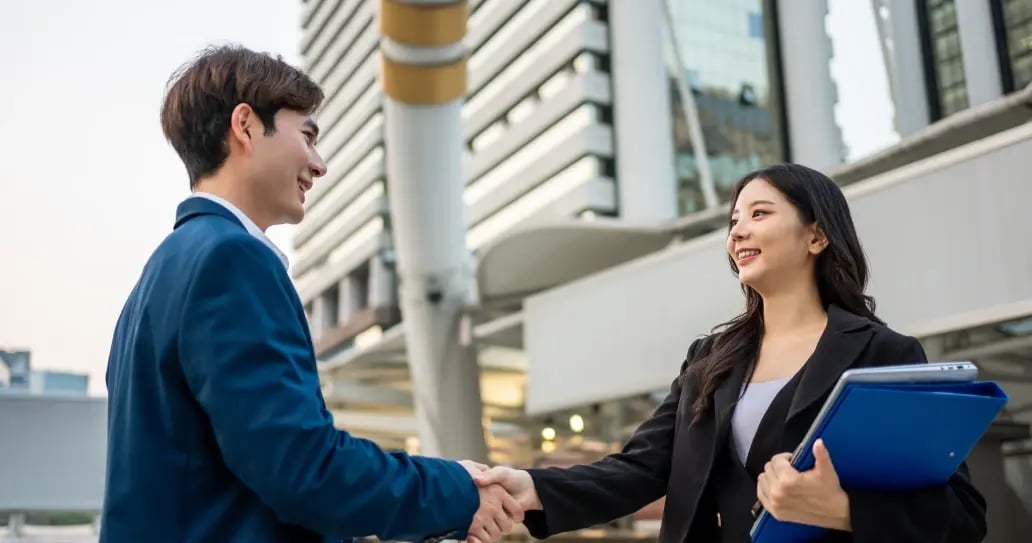 Two business professionals shaking hands in modern Hong Kong financial district after completing secure escrow transaction